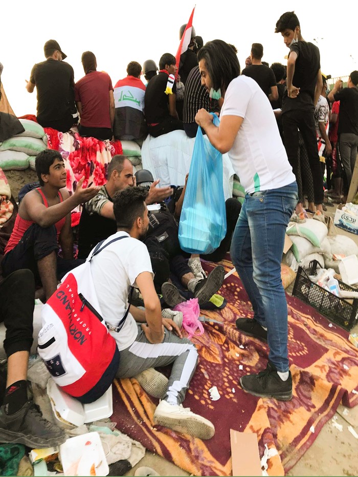 A member of National Baptist Church gives food to protesters in Baghdad.