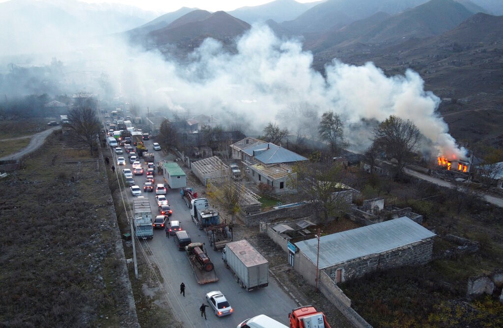 Smoke rises from a burning house as cars and trucks stuck in a huge traffic jam climbing along the road from Kelbajar leaving the separatist region of Nagorno-Karabakh to Armenia on Nov. 14. Smoke rises from a burning house as cars and trucks stuck in a huge traffic jam climbing along the road from Kelbajar leaving the separatist region of Nagorno-Karabakh to Armenia on Nov. 14.