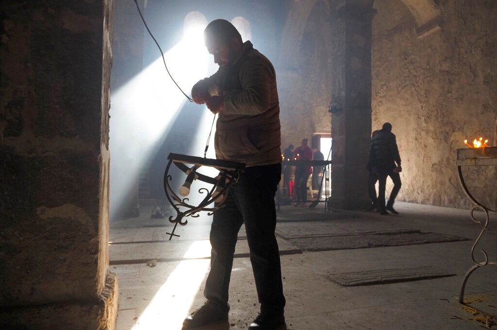 A man removes lamps inside a church of the Dadivank, an Armenian Apostolic Church monastery dating to the ninth century, as ethnic Armenians leave the separatist region of Nagorno-Karabakh to Armenia, Saturday, Nov. 14, 2020.