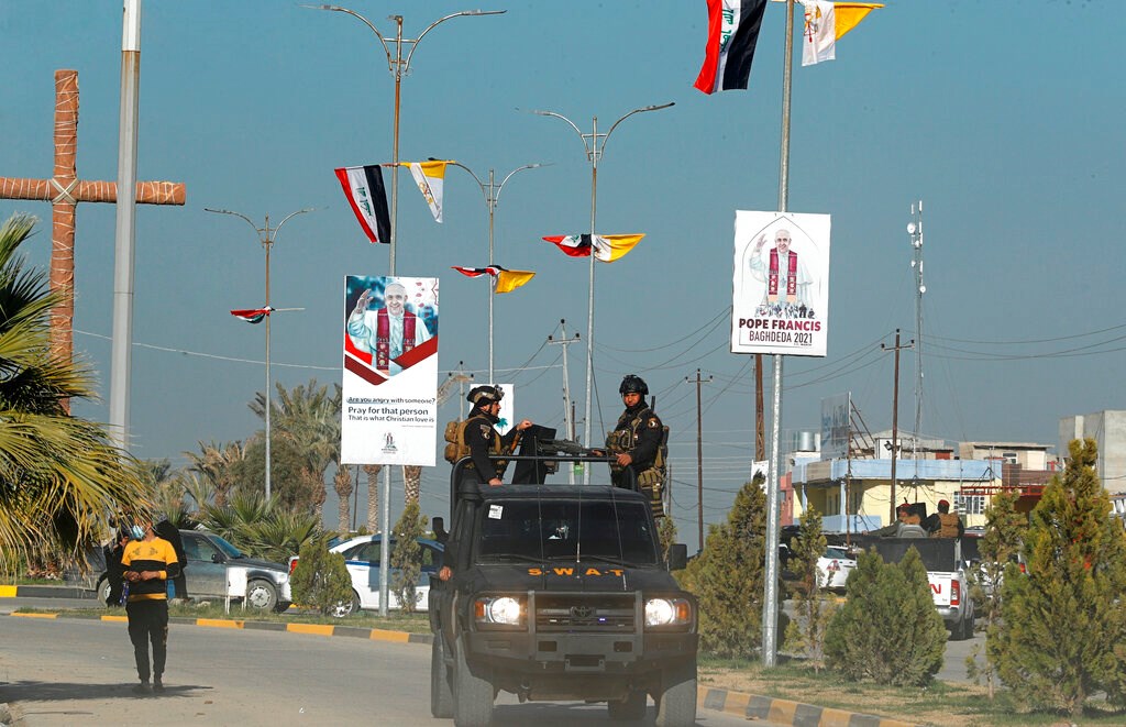 Iraqi security forces in Qaraqosh pass by the flags of Iraq and the Vatican and posters announcing the upcoming visit of Pope Francis on February 22.