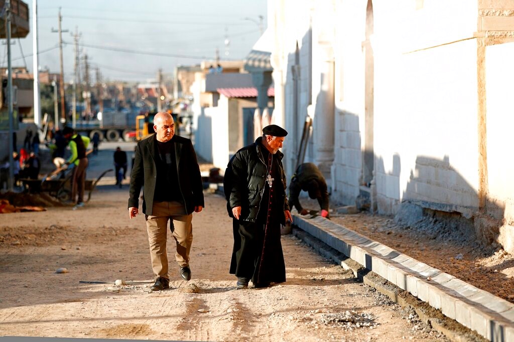 A priest watches workers fix a street destroyed during clashes against Islamic State militants in Qaraqosh, Iraq, on February 23.