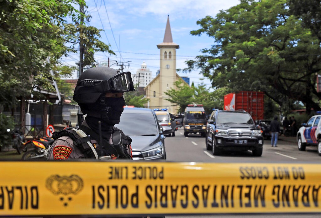 An Indonesian police officer stands guard near the Sacred Heart of Jesus Cathedral in Makassar, South Sulawesi, where an explosion went off on Palm Sunday.