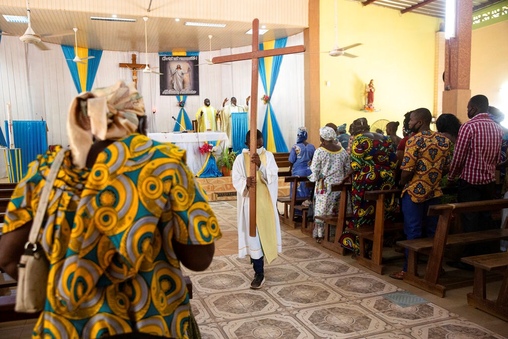 An altar boy carries a cross as Noel Henri Zongo, priest at the Church of the Sangoulé Lamizana military camp in Ouagadougou, Burkina Faso, celebrates Mass on April 11. Just seven chaplains are charged with spiritually advising some 11,000 soldiers and helping maintain their morale.