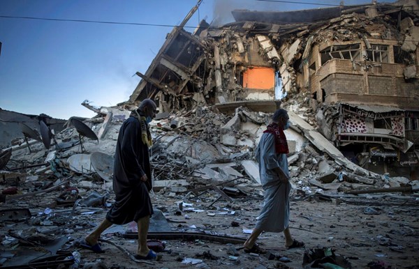 Palestinos caminham ao lado dos escombros de um prédio de 15 andares, atingido por ataques aéreos israelenses à cidade de Gaza, em 13 de maio de 2021. Palestinos caminham ao lado dos escombros de um prédio de 15 andares, atingido por ataques aéreos israelenses à cidade de Gaza, em 13 de maio de 2021.