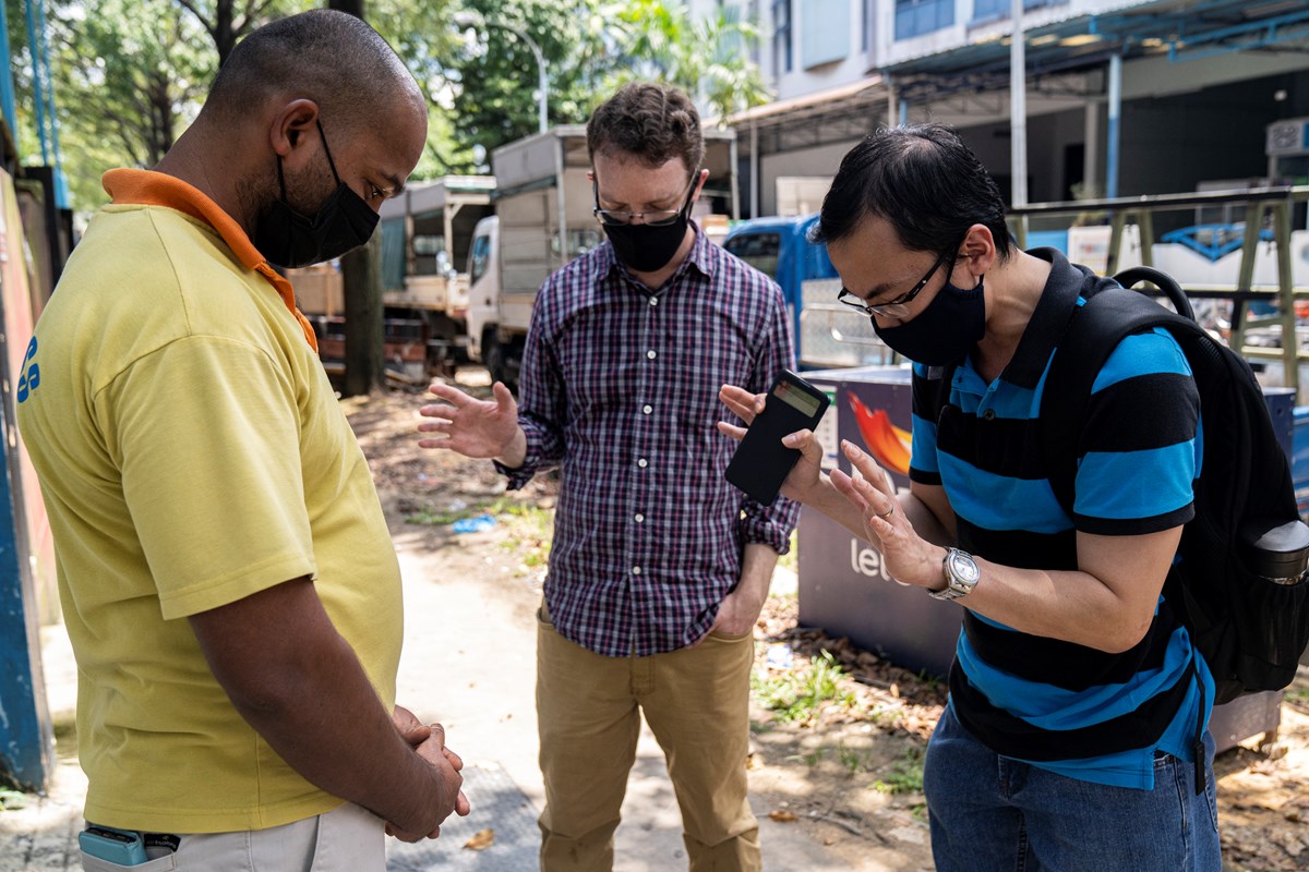 Pastor Guoliang Wong (right) and Thomas Franks (middle) pray together with Francis Xavier (left), a Christian migrant worker outside a factory-converted dormitory in Singapore in April 2020.