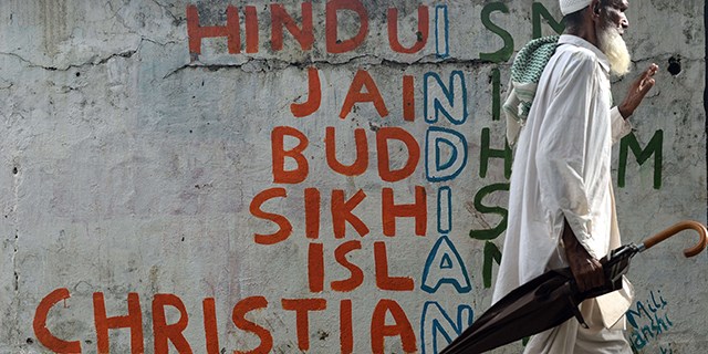 An Indian man walks past a wall graffiti on various religions in Mumbai on June 25, 2015.