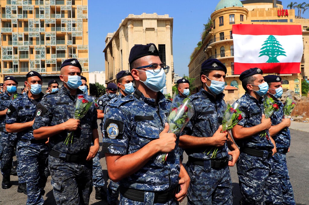 Police hold flowers to mark the first anniversary of Beirut's massive 2020 seaport blast on Wednesday, August 4, 2021. Police hold flowers to mark the first anniversary of Beirut's massive 2020 seaport blast on Wednesday, August 4, 2021.