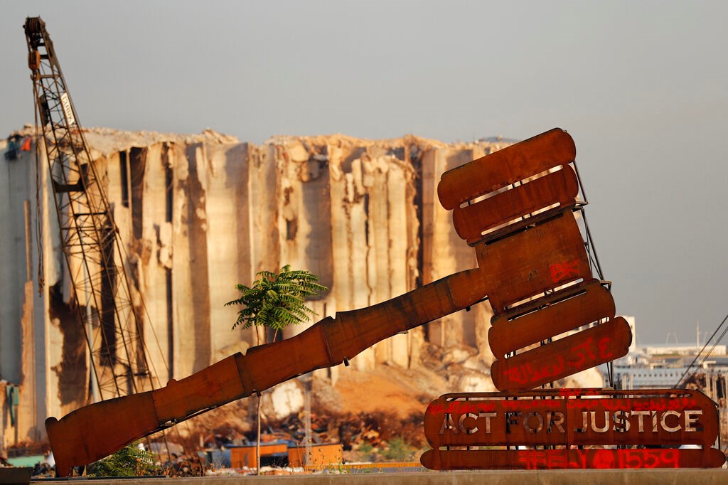 A justice symbol monument is seen in front of towering grain silos that were gutted in the massive August 2020 explosion at the port that claimed the lives of more than 200 people, in Beirut, Lebanon on August 4, 2021. A justice symbol monument is seen in front of towering grain silos that were gutted in the massive August 2020 explosion at the port that claimed the lives of more than 200 people, in Beirut, Lebanon on August 4, 2021.
