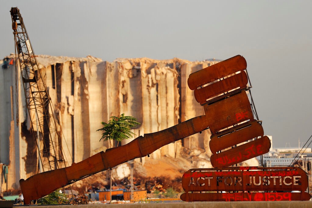 A justice symbol monument is seen in front of towering grain silos that were gutted in the massive August 2020 explosion at the port that claimed the lives of more than 200 people, in Beirut, Lebanon on August 4, 2021.