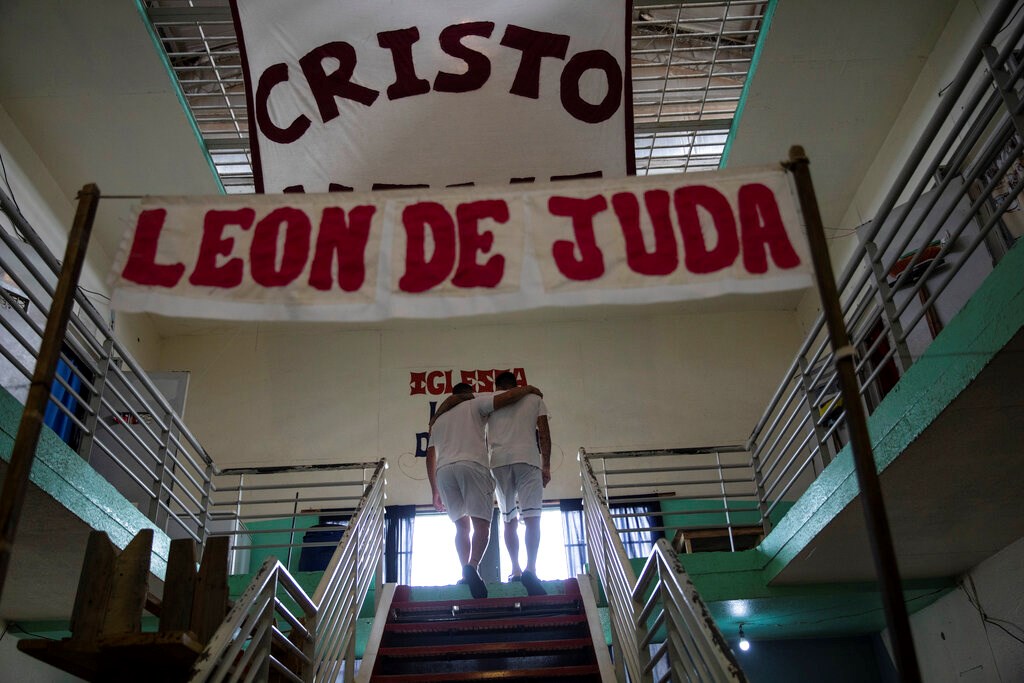 Inmates Ruben Luna, right, who is serving a 14-year sentence for murder, embraces Sebastian Monje, who has been in prison for eight months for attempted murder and robbery, before being baptized inside an evangelical cellblock at the penitentiary in Pinero, Argentina, Saturday, Dec. 11, 2021. The signs read in Spanish "Christ lives. Lion of Judah."
