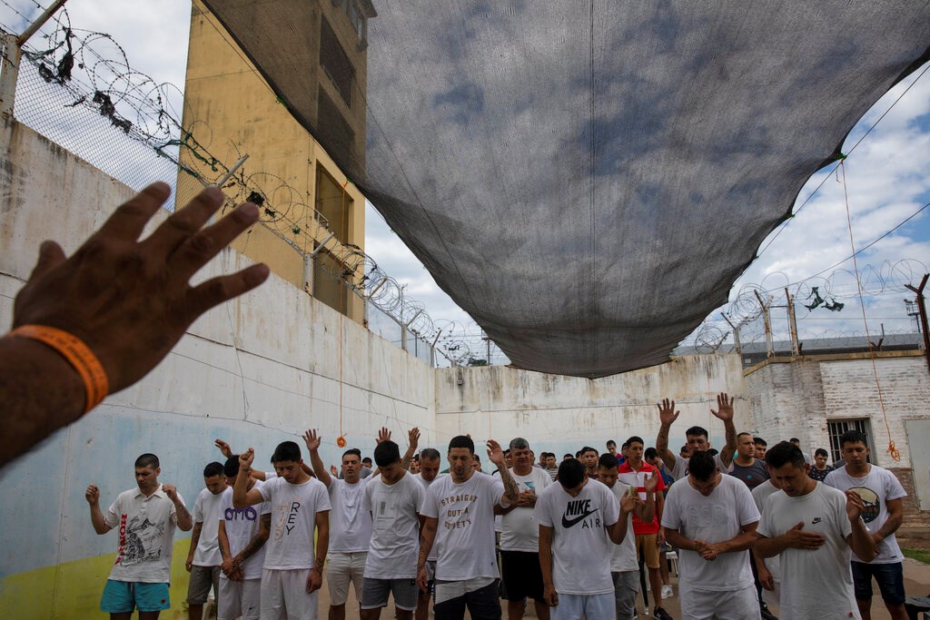 Prisoners pray before getting baptized inside an evangelical cellblock at the Penal Unit N11 penitentiary in Pinero, Santa Fe Province, Argentina, Saturday, Dec. 11, 2021. Prisoners who want to be allowed in an evangelical cellblock must comply with rules of conduct, including praying three times a day, giving up all addictions and fighting.