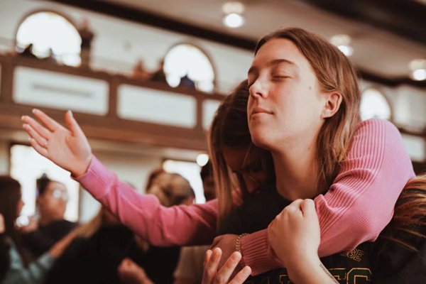 Kebangunan rohani Asbury 2023: Ella Blacey dan Lauren Powell berdoa selama kebaktian di Universitas Asbury.