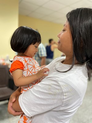 A mother holding her child at the evening of worship at the Delhi Relief facility.