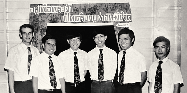 หมอเฮนรี่ (ซ้ายสุด) กำลังยืนถ่ายรูปกับนักศึกษาพระคริสตธรรมกรุงเทพรุ่นแรกในปี คศ.1971 ซึ่งมีอาจารย์ชุมแสง เรืองเจริญสุข อยู่ด้วย (คนที่ 4 จากซ้าย)