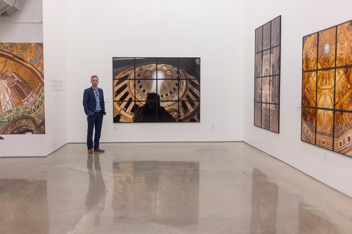 Kieran Dodds next to his work in the exhibit, “Heading Home: Glimpses of New Jerusalem".