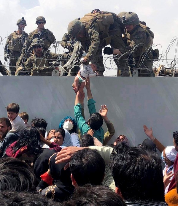 US Marine grabbing an infant over a fence of barbed wire during an evacuation at Hamid Karzai International Airport in Kabul.