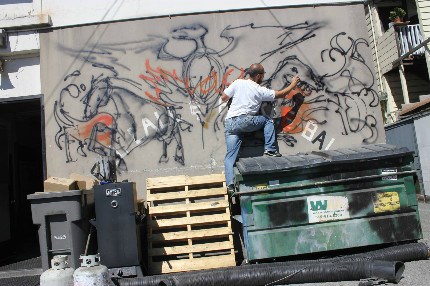 Kim painting dinosaurs on a back wall of the Oakland Fire Department (with permission). Kim painting dinosaurs on a back wall of the Oakland Fire Department (with permission).