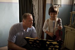 ORCHESTRA OF EXILES director Josh Aronson instructs Henk Reinicke as little Broni Huberman, a child prodigy pushed into the spotlight by his father.