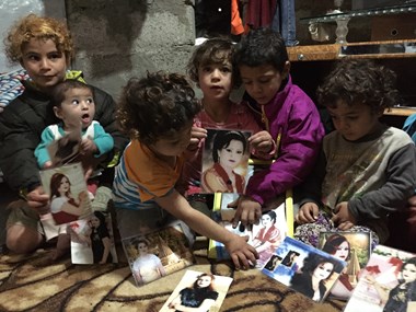 Refugee children from Sinjar display photos of their sister killed by ISIS.