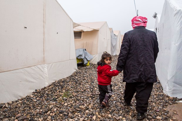 A child walks with her father in Kurdistan's largest refugee camp.
