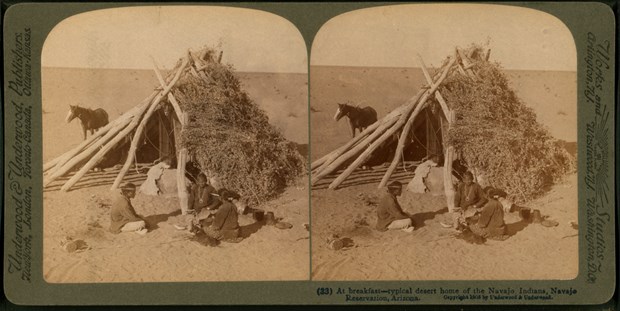 A Navajo family eats breakfast in front of a hogan made of logs and brush. This photo is from around 1903, about 35 years after the Navajo signed a treaty with the United States to establish a reservation in their homeland.