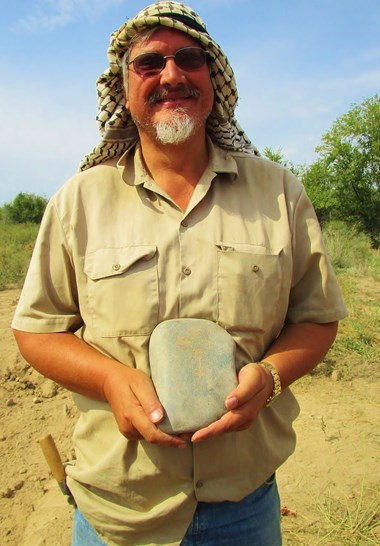 An ancient gravestone inscribed with a cross, held by Thomas Davis of Southwestern Baptist Theological Seminary.