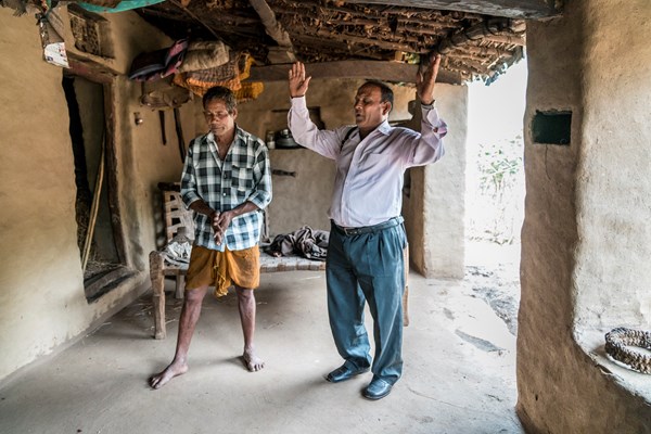 Pastor Bhagwana Lal prays with a tribal neighbor.