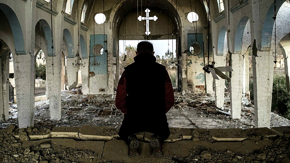 A local Christian prays in the ruins of a church destroyed by ISIS in Syria's Hasakah province.