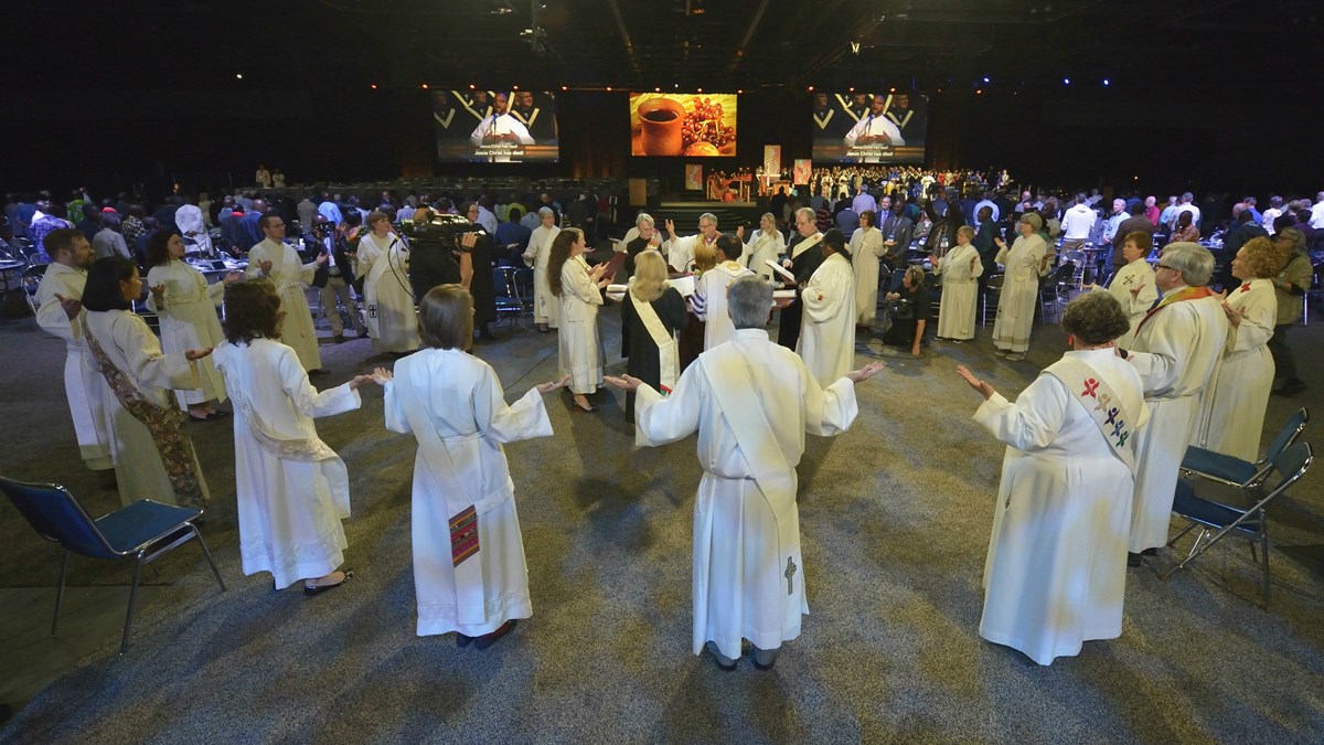 Bishops and deacons surround the communion table during opening worship for the 2016 United Methodist General Conference in Portland, Ore., on May 10. 