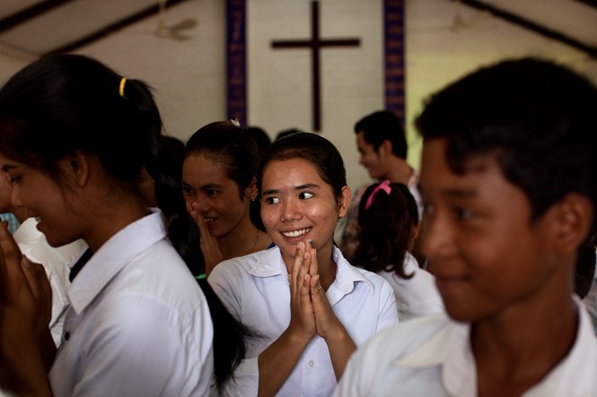 Members of Grace Brethren Church in Battambang extend traditional bows to one another during the passing of the peace.