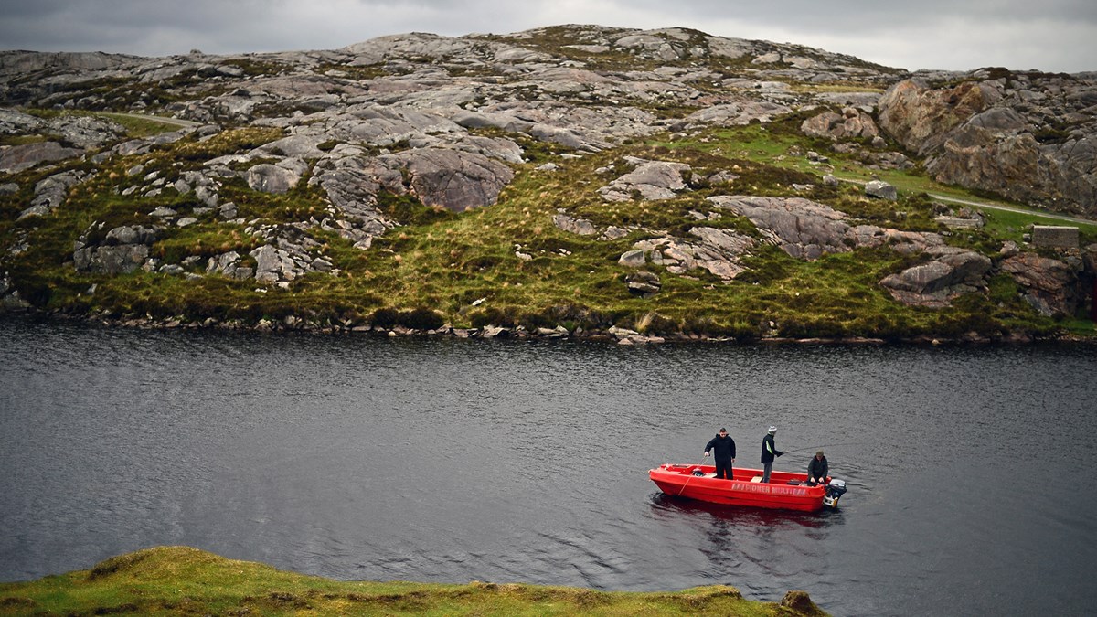 Men fly fish in a boat on a loch in Harris.