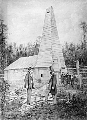 Drake (right) in front of his first oil well