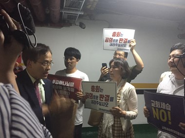 Students and activists question a court member in the parking lot.